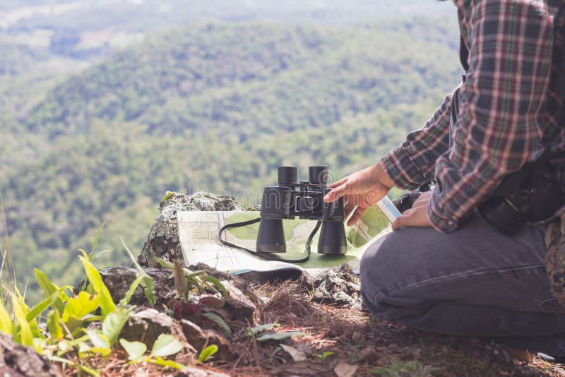 Giovane con lo zaino e la tenuta della seduta del binocolo sopra la montagna, i concetti di turismo e di escursione fotografia stock libera da diritti Giovane con lo zaino e la tenuta della seduta del binocolo sopra la montagna, i concetti di turismo e di escursione fotografia stock libera da diritti