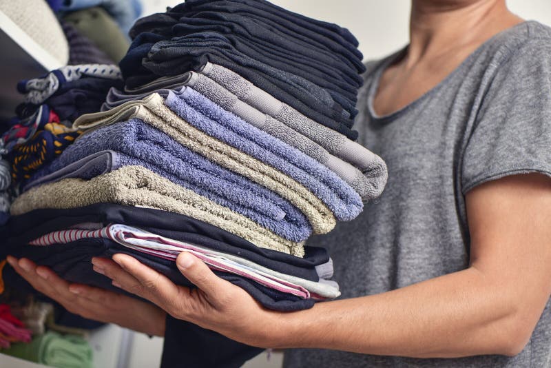 Closeup of a young man carrying a pile of different folded clothes. Closeup of a young man carrying a pile of different folded clothes