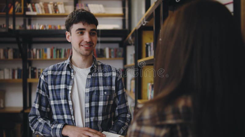 Giovane conversatore amichevole con una donna in una comoda biblioteca nel pomeriggio video d archivio