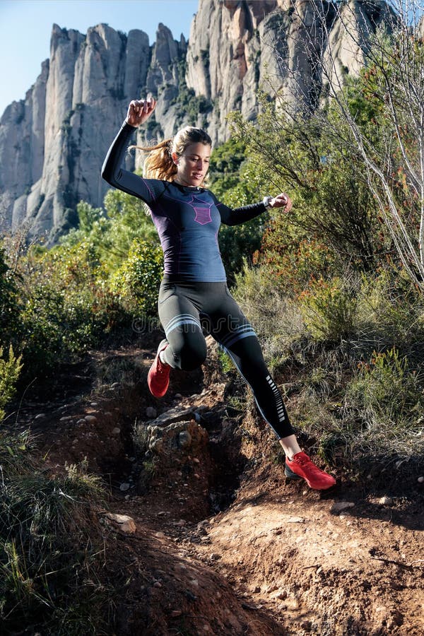 Giovane corridore della traccia della donna di forma fisica che corre e che salta sulla montagna rocciosa immagini stock libere da diritti Giovane corridore della traccia della donna di forma fisica che corre e che salta sulla montagna rocciosa immagini stock libere da diritti