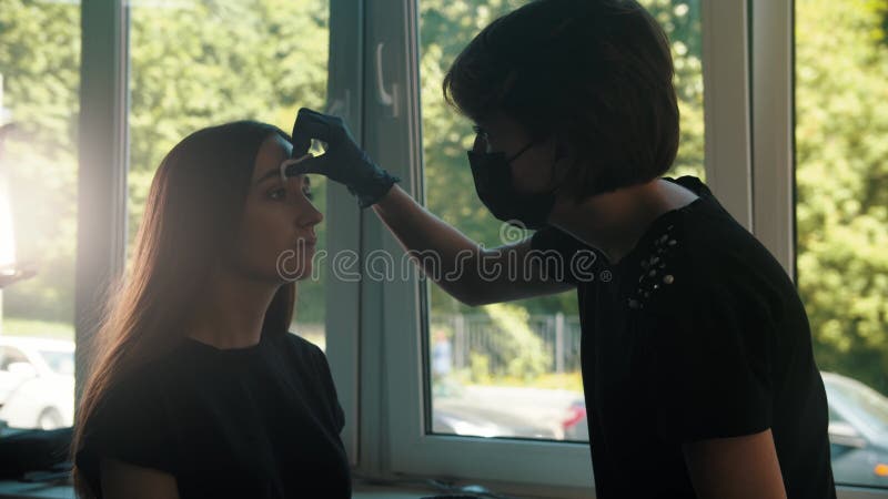 Giovane cosmetologo elimina le sopracciglia del modello stock footage