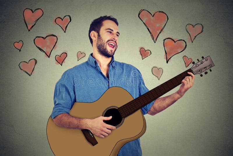 Giovane del musicista bello nell'amore che gioca chitarra e che canta una canzone fotografia stock Giovane del musicista bello nell'amore che gioca chitarra e che canta una canzone fotografia stock