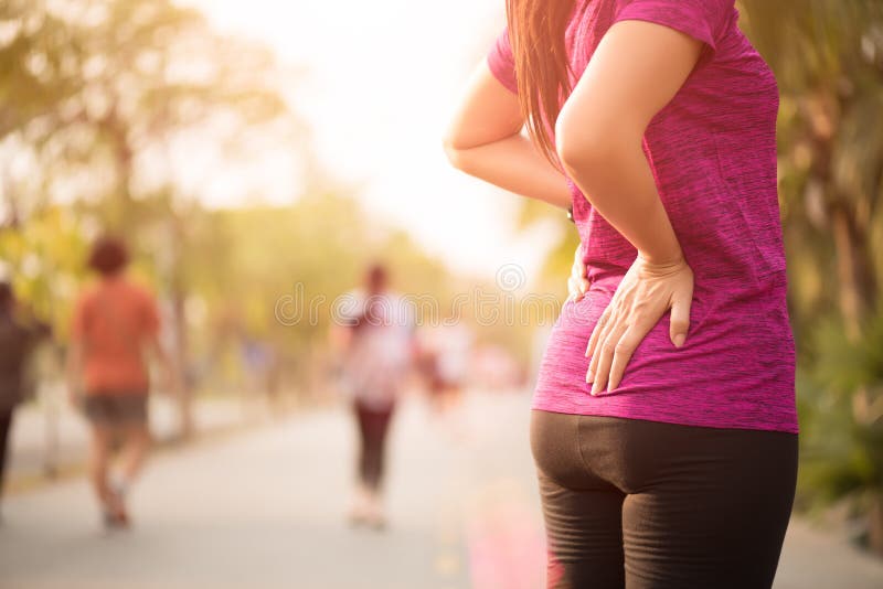 Giovane dolore asiatico di tatto della donna sul suo indietro e sull'anca mentre esercitandosi, concetto di sanità