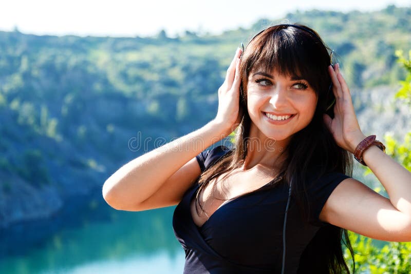 Giovane donna abbastanza allegra che ascolta la musica nel outd delle cuffie fotografie stock Giovane donna abbastanza allegra che ascolta la musica nel outd delle cuffie fotografie stock