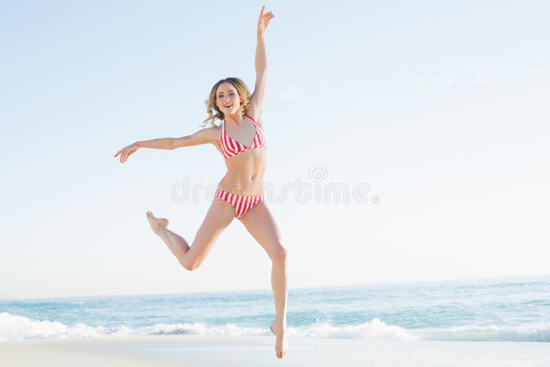 Giovane donna adorabile che salta sulla spiaggia fotografia stock Giovane donna adorabile che salta sulla spiaggia fotografia stock
