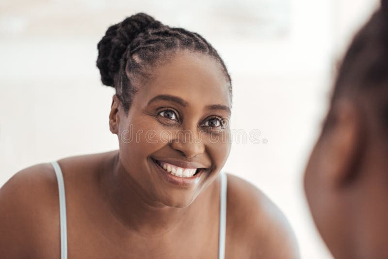 Giovane donna africana che sorride alla sua riflessione in uno specchio fotografie stock