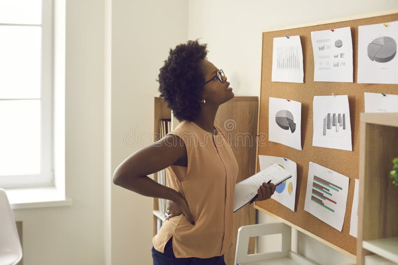Giovane donna afro-americana impiegata a bordo con grafici e grafici immagine stock libera da diritti