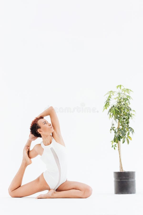 Giovane donna afroamericana attraente che fa allungando gli esercizi di yoga immagini stock libere da diritti Giovane donna afroamericana attraente che fa allungando gli esercizi di yoga immagini stock libere da diritti