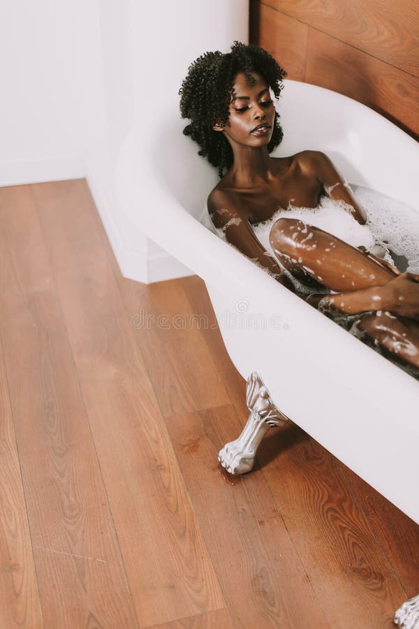 Giovane giovane donna afroamericana che risiede nel bagno con schiuma immagini stock Giovane giovane donna afroamericana che risiede nel bagno con schiuma immagini stock