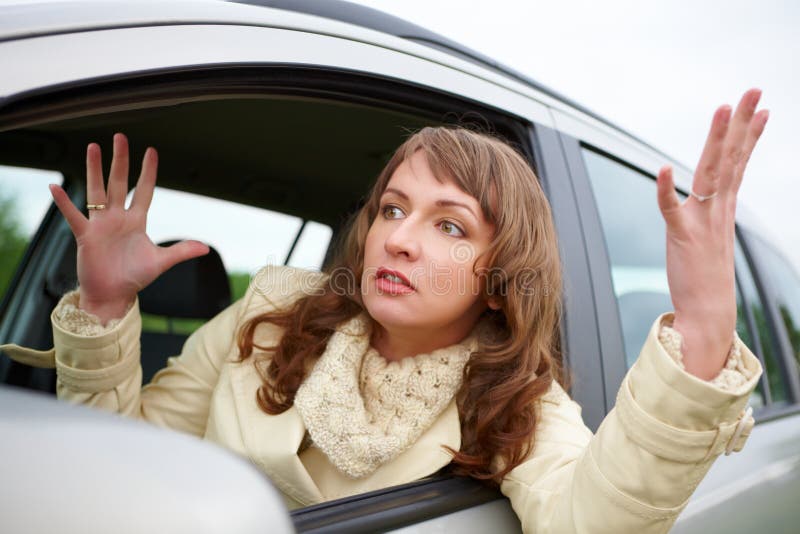 Giovane donna arrabbiata che si siede in un'automobile immagine stock
