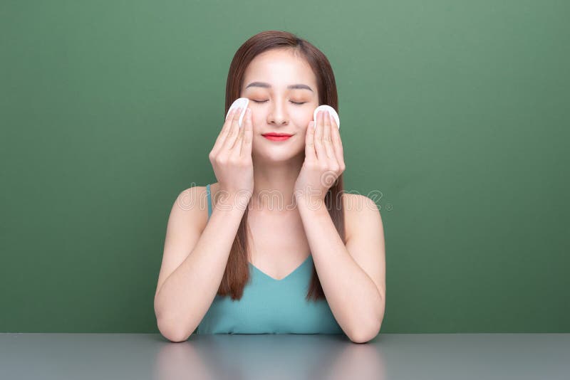 Attractive young Asian woman removes make up with white cosmetic cotton pad. Face skin care. Attractive young Asian woman removes make up with white cosmetic cotton pad. Face skin care.