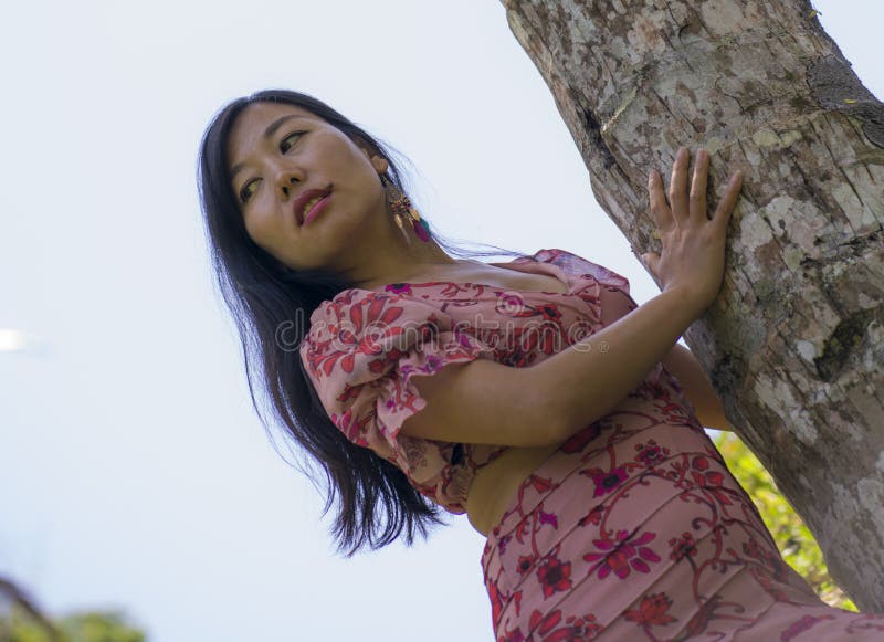 Giovane donna asiatica, bella e rilassata, con elegante abito estivo, che si gode la serenità della bellezza della natura che toc fotografia stock libera da diritti Giovane donna asiatica, bella e rilassata, con elegante abito estivo, che si gode la serenità della bellezza della natura che toc fotografia stock libera da diritti