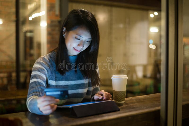 Giovane donna asiatica che utilizza compressa per l'acquisto online nel caffè fotografie stock libere da diritti Giovane donna asiatica che utilizza compressa per l'acquisto online nel caffè fotografie stock libere da diritti