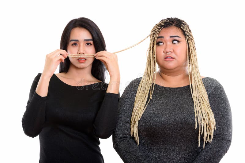 Giovane donna asiatica del transessuale che per mezzo dei capelli della donna asiatica grassa alla m. immagine stock Giovane donna asiatica del transessuale che per mezzo dei capelli della donna asiatica grassa alla m. immagine stock