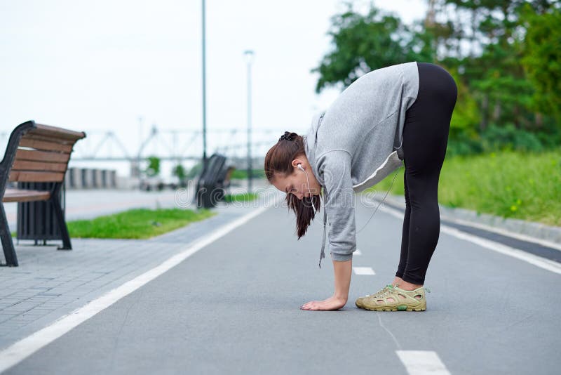 Giovane donna asiatica di forma fisica che allunga le gambe dopo il funzionamento all'aperto dopo il funzionamento fotografia stock Giovane donna asiatica di forma fisica che allunga le gambe dopo il funzionamento all'aperto dopo il funzionamento fotografia stock