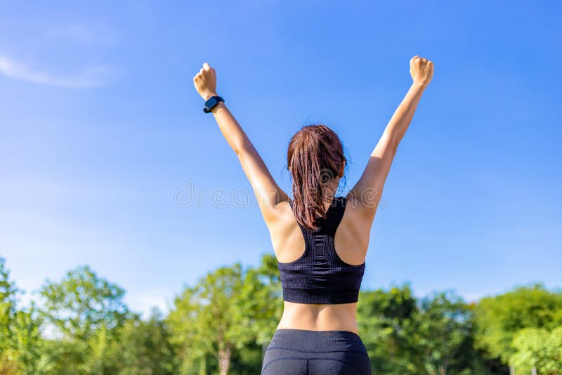 Giovane donna asiatica felice che alza sulle sue armi allegramente dopo completo la sua routine di esercizio ad un parco all'aper fotografia stock libera da diritti Giovane donna asiatica felice che alza sulle sue armi allegramente dopo completo la sua routine di esercizio ad un parco all'aper fotografia stock libera da diritti