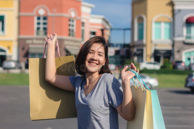 Giovane donna asiatica felice che compera un mercato all'aperto immagine stock libera da diritti Giovane donna asiatica felice che compera un mercato all'aperto immagine stock libera da diritti