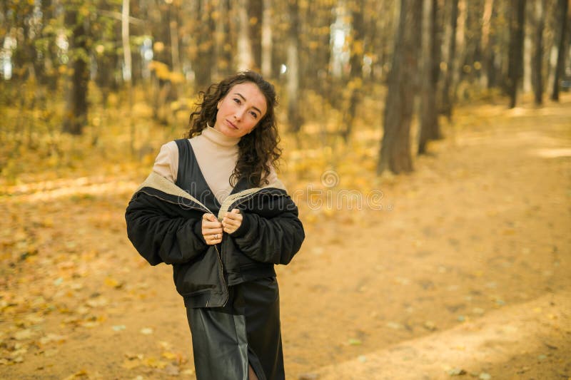 Giovane donna attraente che cammina nel parco autunnale felice umore e moda stile moda e capelli castani ricci. stagione di caduta fotografie stock libere da diritti