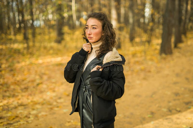 Giovane donna attraente che cammina nel parco autunnale felice umore e moda stile moda e capelli castani ricci. stagione di caduta fotografia stock libera da diritti