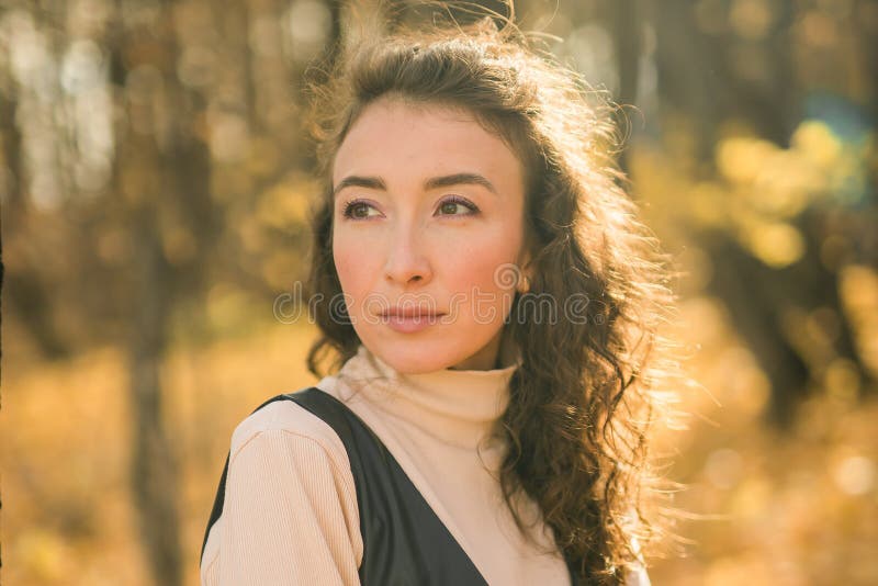 Giovane donna attraente che cammina nel parco autunnale felice umore e moda stile moda e capelli castani ricci. stagione di caduta immagini stock
