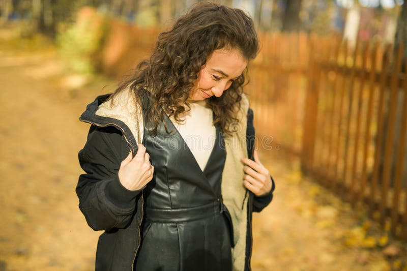 Giovane donna attraente che cammina nel parco autunnale felice umore e moda stile moda e capelli castani ricci. stagione di caduta immagini stock libere da diritti