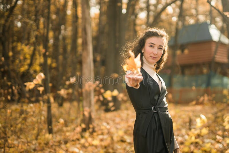 Giovane donna attraente che cammina nel parco autunnale felice umore e moda stile moda e capelli castani ricci. stagione di caduta fotografia stock libera da diritti