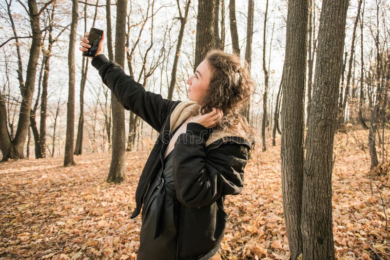 Giovane donna attraente che cammina nel parco autunnale felice umore e moda stile moda e capelli castani ricci. stagione di caduta immagini stock
