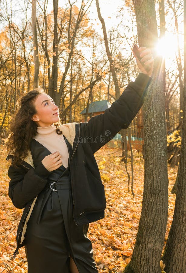 Giovane donna attraente che cammina nel parco autunnale felice umore e moda stile moda e capelli castani ricci. stagione di caduta immagine stock libera da diritti