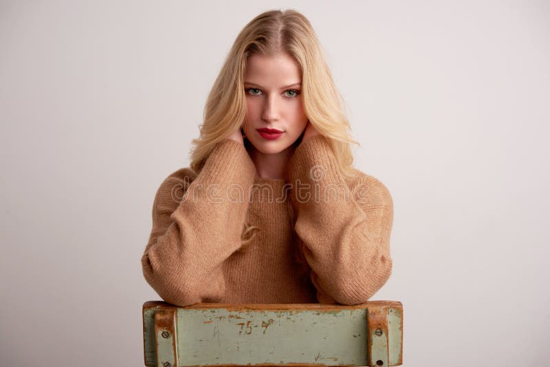 Giovane donna attraente con capelli biondi e rossetto rosso seduto su uno sfondo isolato fotografia stock