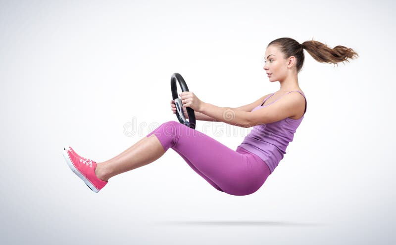 Giovane donna in automobile rosa dell'autista degli abiti sportivi con il volante, concetto automatico immagini stock libere da diritti Giovane donna in automobile rosa dell'autista degli abiti sportivi con il volante, concetto automatico immagini stock libere da diritti