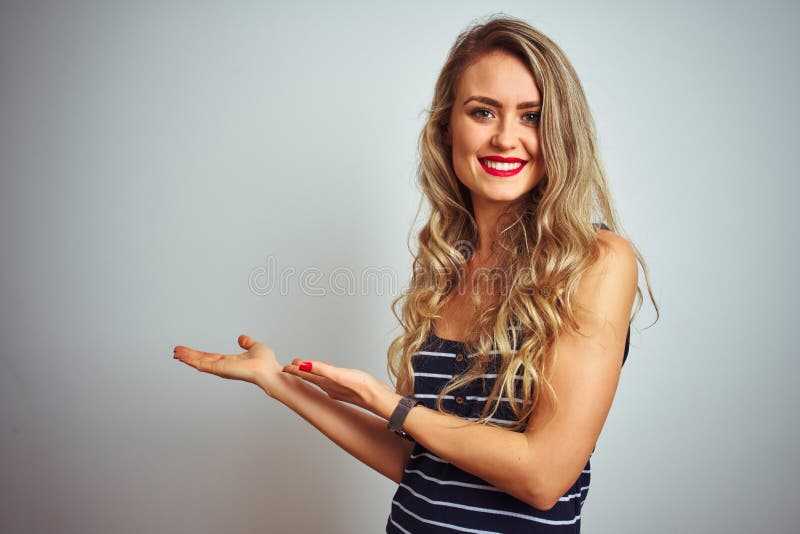 Giovane donna bella con una camicia a strisce in piedi su fondo bianco isolato, che invita ad entrare naturale sorridente con una immagine stock
