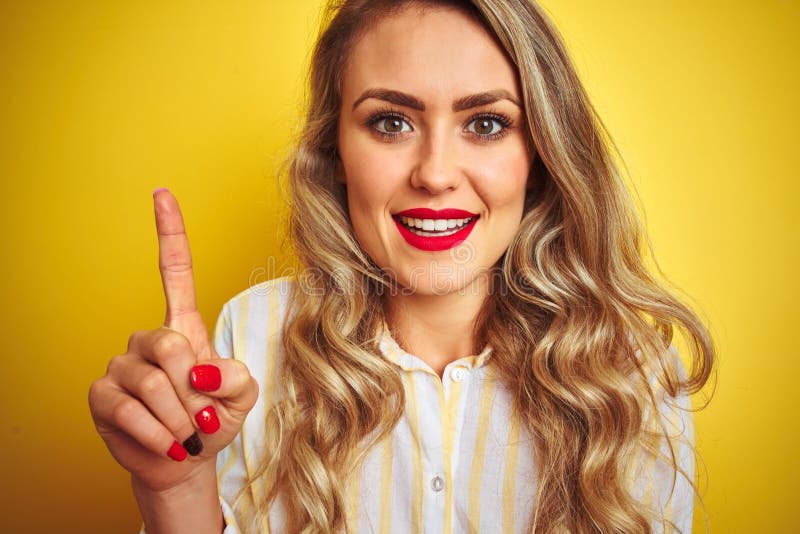Giovane donna bella con una camicia a strisce in piedi su fondo giallo isolato sorpresa di un'idea o di una domanda che punta fotografie stock libere da diritti