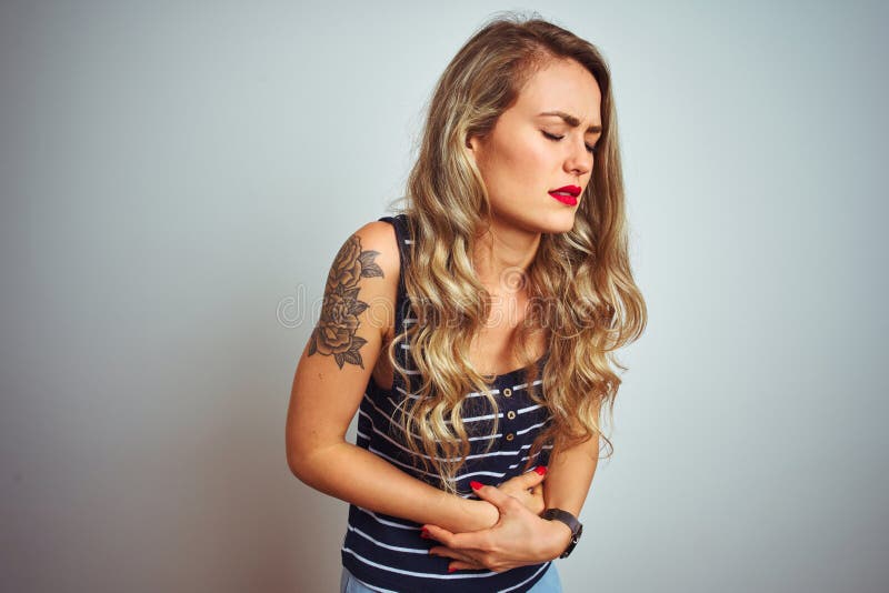 Giovane donna bella con una camicia a strisce sullo sfondo bianco isolato con la mano sullo stomaco per l'indigestione fotografia stock libera da diritti