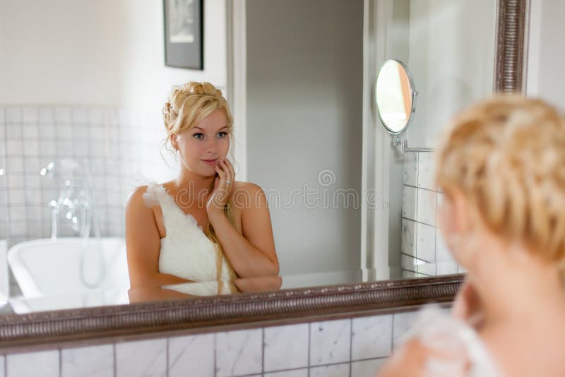 Giovane donna bionda sexy che loking allo specchio in bagno immagine stock libera da diritti Giovane donna bionda sexy che loking allo specchio in bagno immagine stock libera da diritti