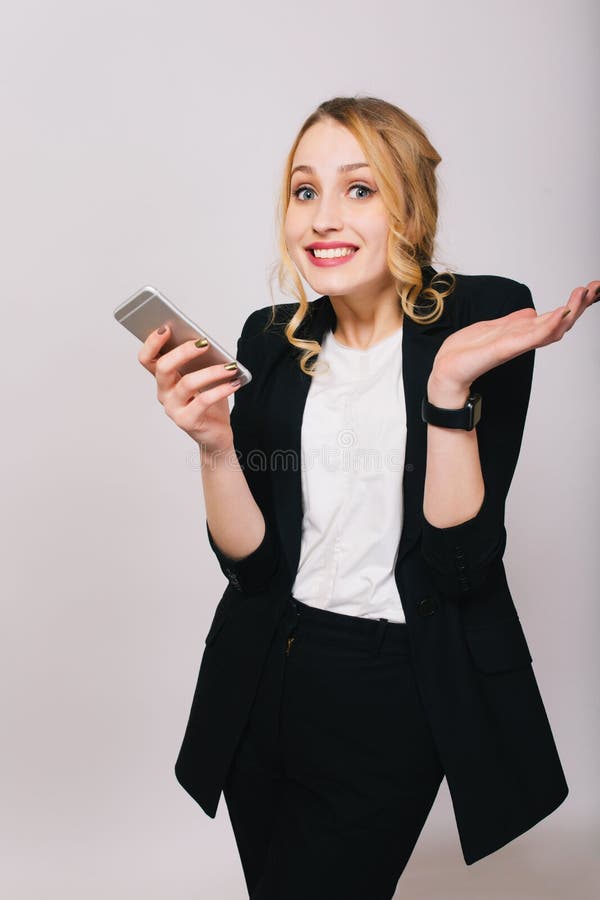 Giovane donna bionda sveglia dell'ufficio in camicia bianca, vestito nero con il telefono che esamina macchina fotografica isolat immagini stock libere da diritti Giovane donna bionda sveglia dell'ufficio in camicia bianca, vestito nero con il telefono che esamina macchina fotografica isolat immagini stock libere da diritti
