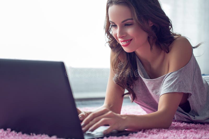 Giovane donna caucasica che scrive sul computer portatile su tappeto fotografia stock Giovane donna caucasica che scrive sul computer portatile su tappeto fotografia stock