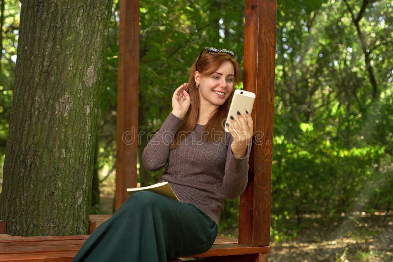 Giovane donna che ammira la sua riflessione nel telefono fotografia stock Giovane donna che ammira la sua riflessione nel telefono fotografia stock