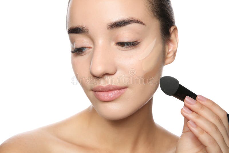 Giovane donna che applica fondamento sul suo fronte immagini stock Giovane donna che applica fondamento sul suo fronte immagini stock