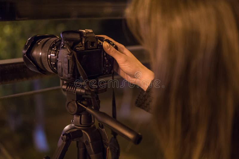 Giovane donna che esamina l'esposizione la notte, primo piano della macchina fotografica fotografia stock Giovane donna che esamina l'esposizione la notte, primo piano della macchina fotografica fotografia stock