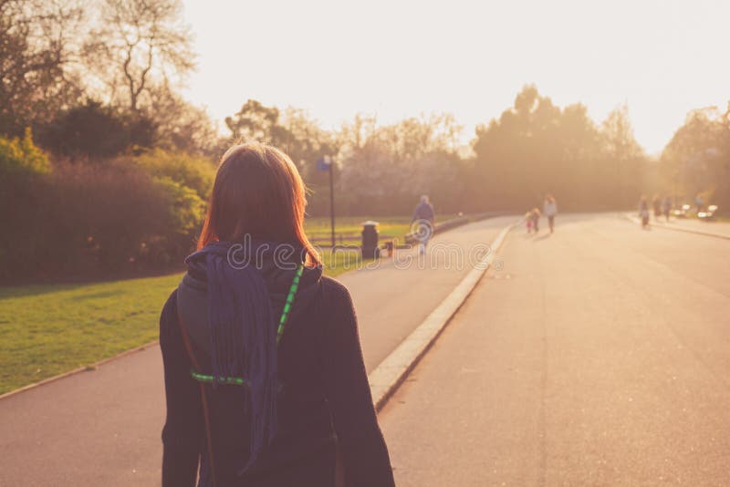 Giovane donna che esamina tramonto in parco fotografia stock libera da diritti Giovane donna che esamina tramonto in parco fotografia stock libera da diritti