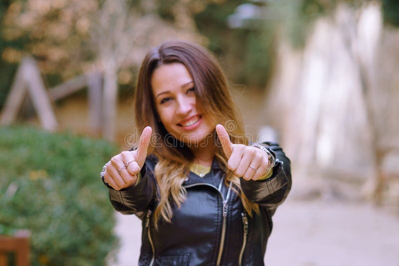 Giovane donna che gesturing pollice su in parco fotografia stock libera da diritti