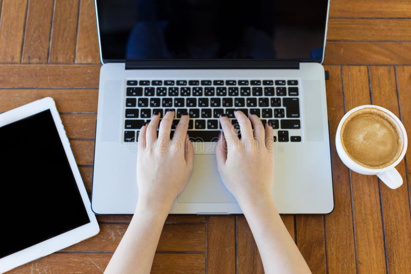Giovane donna che lavora al computer portatile disposto sullo scrittorio di legno Vista superiore fotografia stock libera da diritti Giovane donna che lavora al computer portatile disposto sullo scrittorio di legno Vista superiore fotografia stock libera da diritti