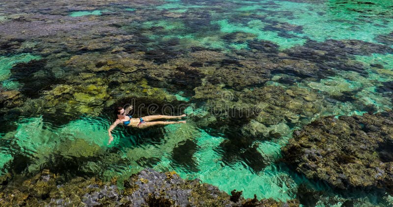 Giovane donna che nuota sopra la barriera corallina su un'isola tropicale