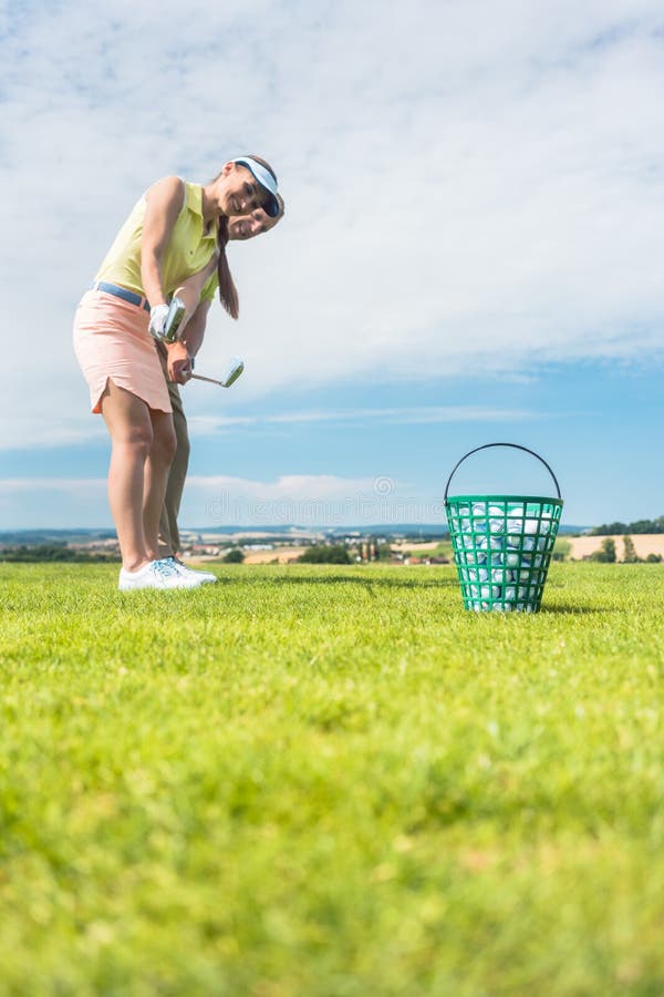 Giovane donna che pratica il movimento corretto durante la classe di golf con fotografia stock libera da diritti Giovane donna che pratica il movimento corretto durante la classe di golf con fotografia stock libera da diritti