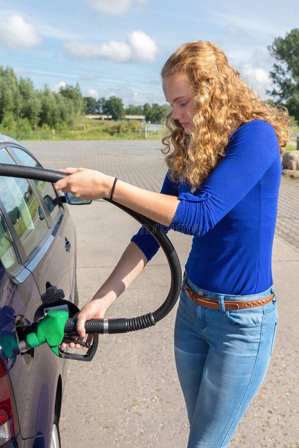 Giovane donna che rifornisce il carro armato di combustibile dell'automobile con benzina immagini stock libere da diritti Giovane donna che rifornisce il carro armato di combustibile dell'automobile con benzina immagini stock libere da diritti