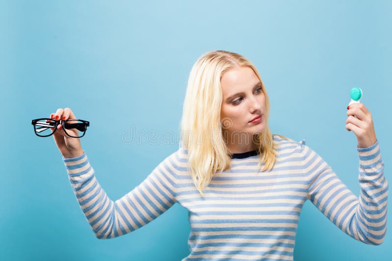 Giovane donna che sceglie fra le lenti a contatto o i vetri fotografia stock libera da diritti Giovane donna che sceglie fra le lenti a contatto o i vetri fotografia stock libera da diritti