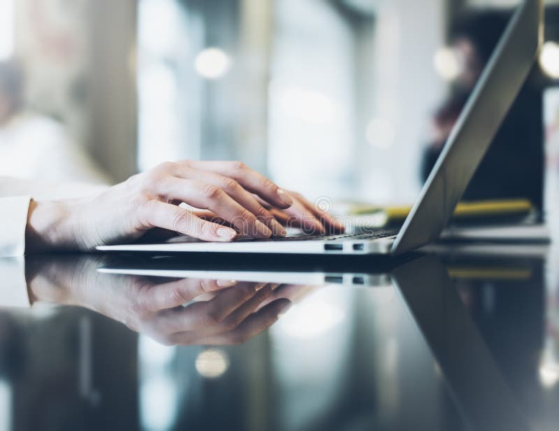Giovane donna che scrive le mani di testo sul computer portatile aperto in un caffè su una tavola con abbagliamento di riflession fotografie stock Giovane donna che scrive le mani di testo sul computer portatile aperto in un caffè su una tavola con abbagliamento di riflession fotografie stock