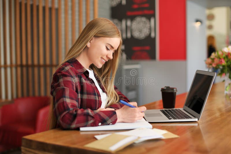 Giovane donna che scrive lettera alla tavola in caffè consegna di posta fotografie stock Giovane donna che scrive lettera alla tavola in caffè consegna di posta fotografie stock