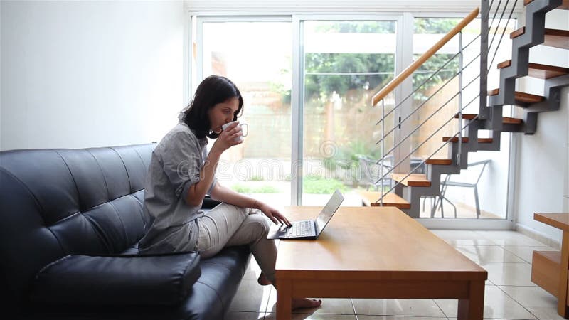 Giovane donna che scrive sul computer portatile a casa video d archivio
