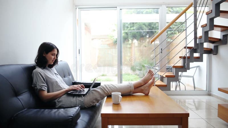 Giovane donna che scrive sul computer portatile a casa accogliente stock footage